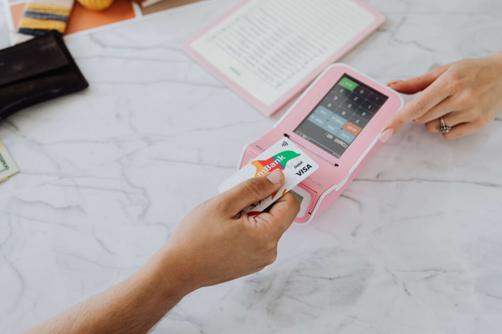Two hands making a contactless card payment at a payment terminal on a marble table