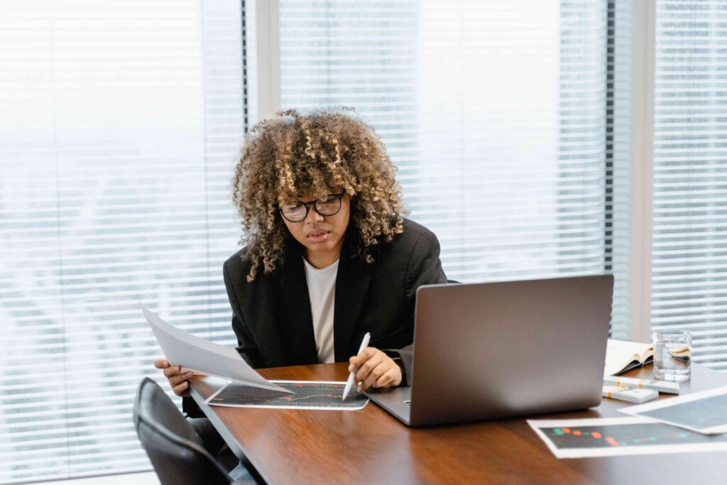 A young professional studies financial charts on a laptop at a modern office desk